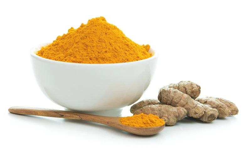 Bol de poudre de curcuma avec racine de curcuma fraîche