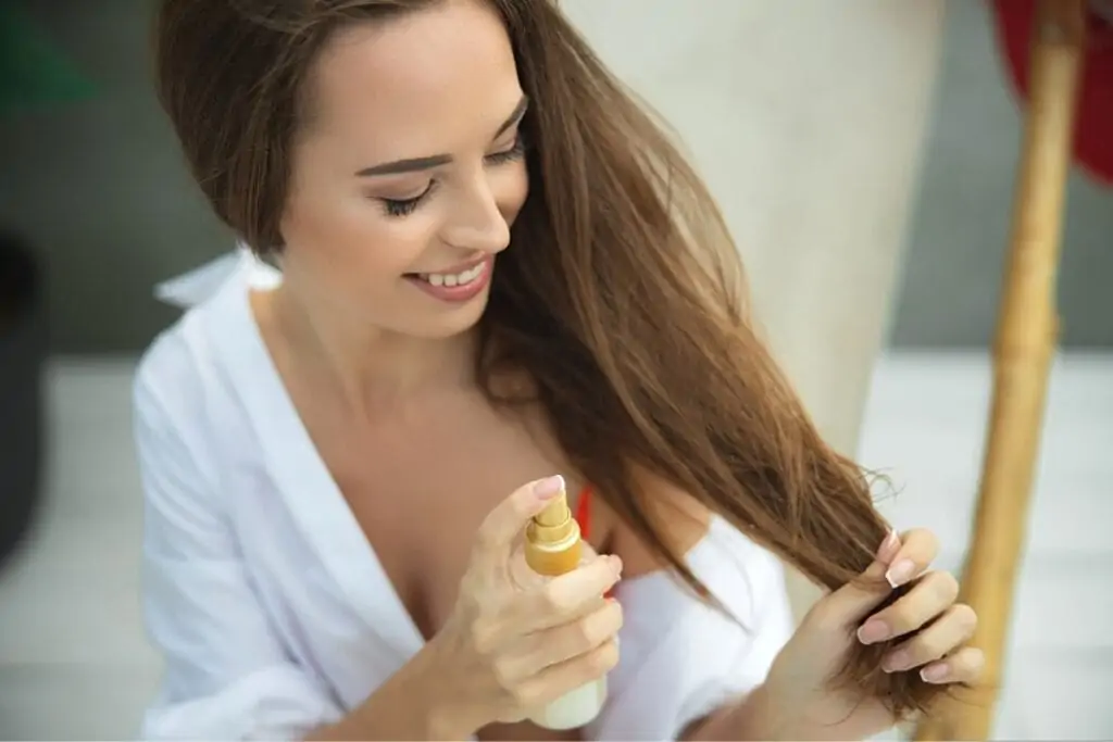 Woman applying sea salt hair spray to hair.
