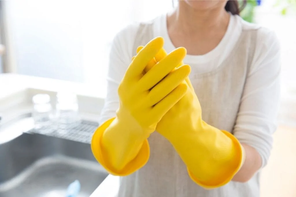 Woman putting on rubber gloves to prevent dry hands.